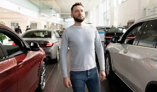 El comprador examina la gama de coches nuevos en la sala de exposición del distribuidor Imágenes de stock libres de derechos