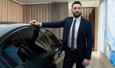 Mutlu, pozitif gülümseyen, güzel, çekici, kıvırcık saçlı, samimi duyguları olan, şık bej gömlekli bir kadının portresi. Mavi duvarın üzerinde izole edilmiş, boş alan olan pembe domuz sikkesi bankası var.