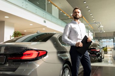 Bir sigorta şirketinin çalışanı, bir araba galerisinde sürücü ve yolcular için sigorta poliçesi hazırlar.