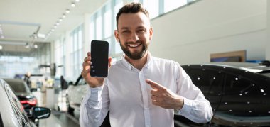 Bir araba galerisinin karizmatik arkadaş canlısı shawarma yöneticisi akıllı telefon ekranını gösteriyor