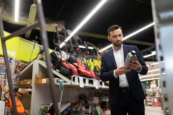 man choosing motor oil for petrol lawn mower at garden supply store