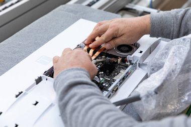 Minsk, Belarus - 15 Aralık 2021: Monoblock montaj fabrikasında bilgisayar monitör sistemi bloğu montajlayan bir adamın fotoğrafları. Mühendis modern bir yüksek teknoloji fabrikasında çalışıyor.