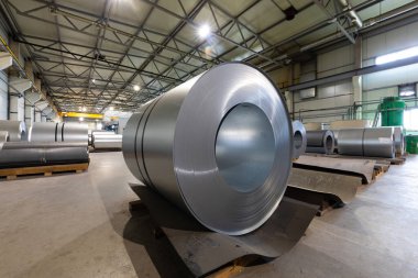 Metalik makine üretim hattının çatısındaki metal fayansların yakından çekilmiş fotoğrafı. Fabrikada soğuk çelik bobinler var.