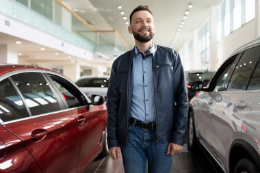 a man chooses a new car for himself walks between the rows in a car dealership