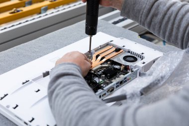 Monoblock montaj fabrikasındaki bir taşıma bandında bilgisayar monitör sistemi bloğu kuran bir adamın el fotoğrafı. Modern yüksek teknoloji fabrikası