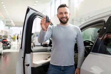 Aldığı ve sigortaladığı arabanın yanında orta yaşlı bir adam kontak anahtarını gösteriyor.