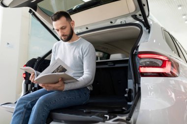 Orta yaşlı bir adam araba sigortası için sigorta şirketinin teklifini inceliyor.