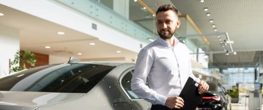 Bir araba galerisinde yeni bir sedan yanında prezentabl sigorta acentesi.