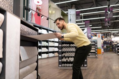 Hırdavatçıdaki bir adam duvarlar için malzeme seçiyor.