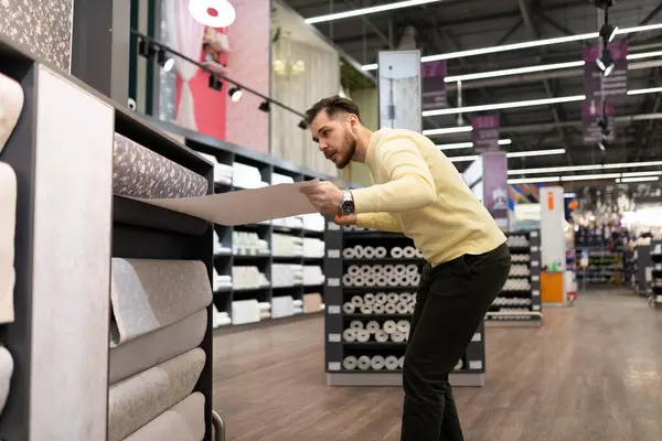 Hırdavatçıdaki bir adam duvarlar için malzeme seçiyor.