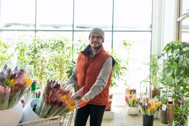 Çiçekçide bir sepet dolusu lalesi olan bir adam..