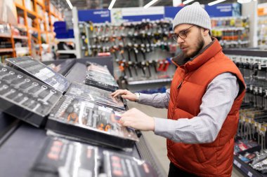 Bir adam bir alet dükkanında arabasını tamir etmek için bir çift soket seçer..