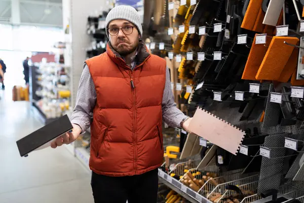 a man cant figure out the difference between two wall plastering tools in a hardware store.