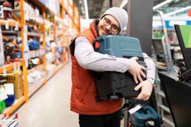 İnşaat hipermarketinde elektrikli süpürgeye sarılan mutlu müşteri..