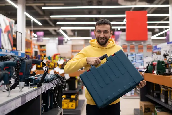 Satisfied buyer of a power tool store holding a case with a smile.