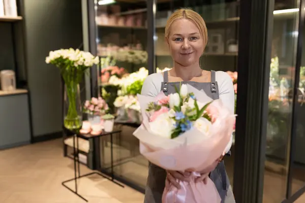 an employee of a florists shop demonstrates a ready-made bouquet to a customer.