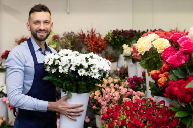 Çiçek satışı için toptan satış yapan bir çalışan elinde buketler olan büyük bir vazo tutuyor..