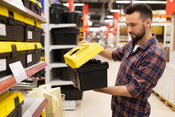 a male builder in a hardware store chooses a tool storage case.