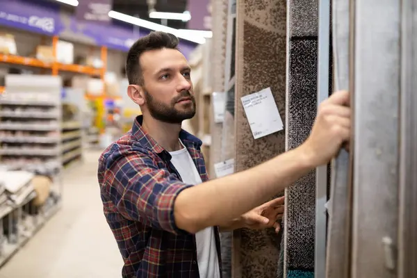 male buyer in a hardware store chooses carpet flooring.