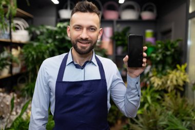 çiçekçi yöneticisi akıllı telefon ekranı gösteriyor.