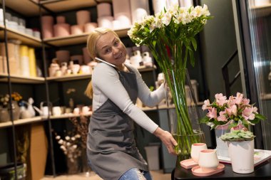 Çiçekçi telefonla sipariş alır ve çiçek buketleri toplar..