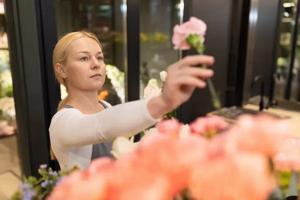 designer of a florist shop chooses flowers for a future bouquet.