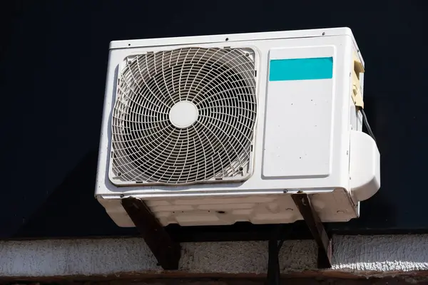 outdoor unit of a domestic air conditioner with a fan outside the building.