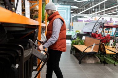 Bir adam kır evi için bahçe mobilyalarını seçer..