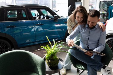 Araba galerisinde evli bir çift yeni bir araba seti seçiyor..