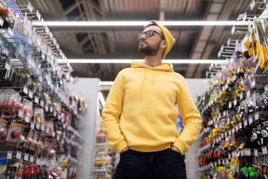 Hırdavatçıda çalışan bir adam raflardaki çeşitli malları inceliyor..