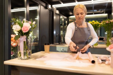 Çiçekçi taze çiçeklerden bir düğün buketi yapar..