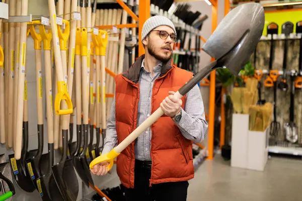 building materials stores a man chooses a new hammer.