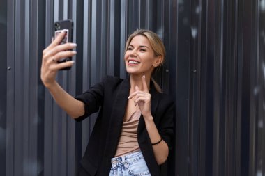 Genç bir kadın ofiste gri duvara karşı konuşuyor..