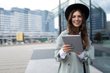 Üniversitenin cam cephesinde tabletli bir öğrencinin portresi..