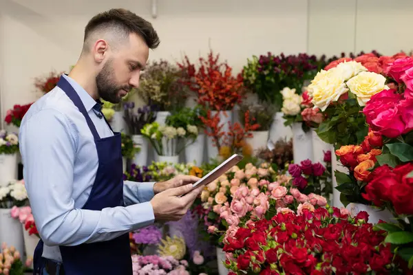 experienced florists with a clipboard among the flowers in the fridge.