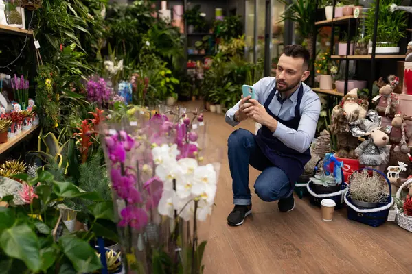 an employee in a flower shop takes a photo of bouquets on the phone.