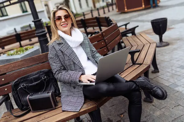 adult successful woman entrepreneur working on laptops in city square online.