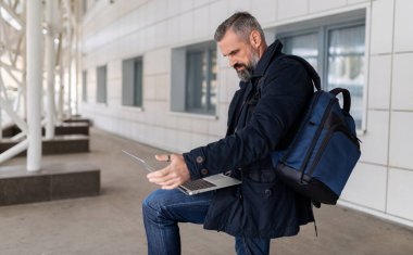 Yetişkin bir girişimci havaalanı salonunda dizüstü bilgisayarla çalışıyor..