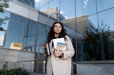 Bir ofis binasının arka planında dizüstü bilgisayarı olan başarılı genç bir iş adamının portresi..