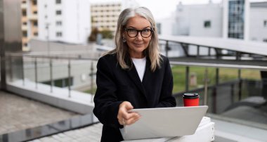 Ofis dışında dizüstü bilgisayarda çalışan şık yaşlı bir yönetici..