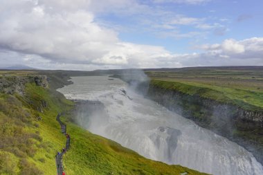 İzlanda 'nın en ünlü şelalesi Gullfoss' tan (Altın Şelale) yükselen sis nedeniyle ziyaretçiler bir patika boyunca yürüyorlar..