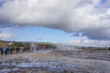 Haukadalur, İzlanda: Ziyaretçiler aktif Strokkur gayzerinin patlamasını bekliyorlar. Her birkaç dakikada bir havaya su ve buhar gönderir..