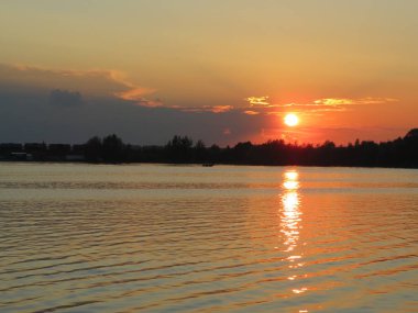 Gölde güneşli bir yaz günbatımı. Batan güneşin ışınları suyun yüzeyine güzel bir şekilde yansıyor..