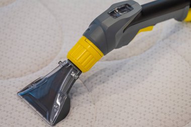 İşçi, elektrikli süpürgeyle yatak temizliyor. Çıkarma yöntemi..