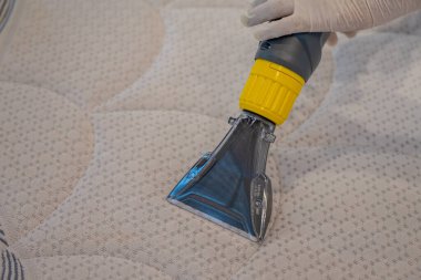 İşçi, elektrikli süpürgeyle yatak temizliyor. Çıkarma yöntemi..