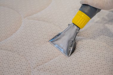 İşçi, elektrikli süpürgeyle yatak temizliyor. Çıkarma yöntemi..