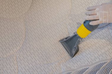 İşçi, elektrikli süpürgeyle yatak temizliyor. Çıkarma yöntemi..