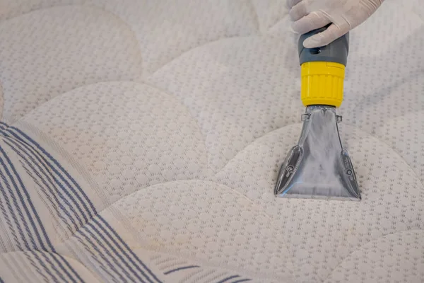 Worker Cleaning a bed with Vacuum Cleaner.Extraction method.