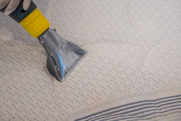 Worker Cleaning a bed with Vacuum Cleaner.Extraction method.