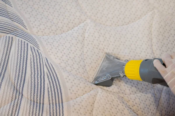 Worker Cleaning a bed with Vacuum Cleaner.Extraction method.